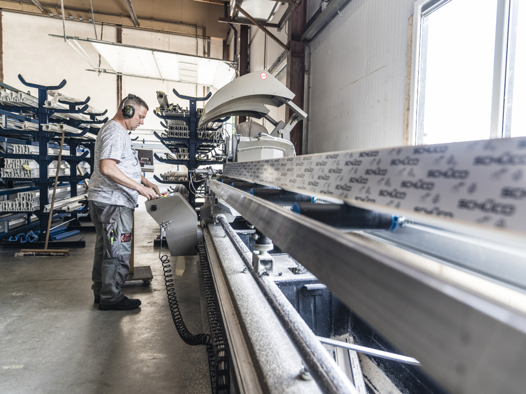 Fabrieksmedewerker stelt een Schüco kozijn samen op de productielijn.